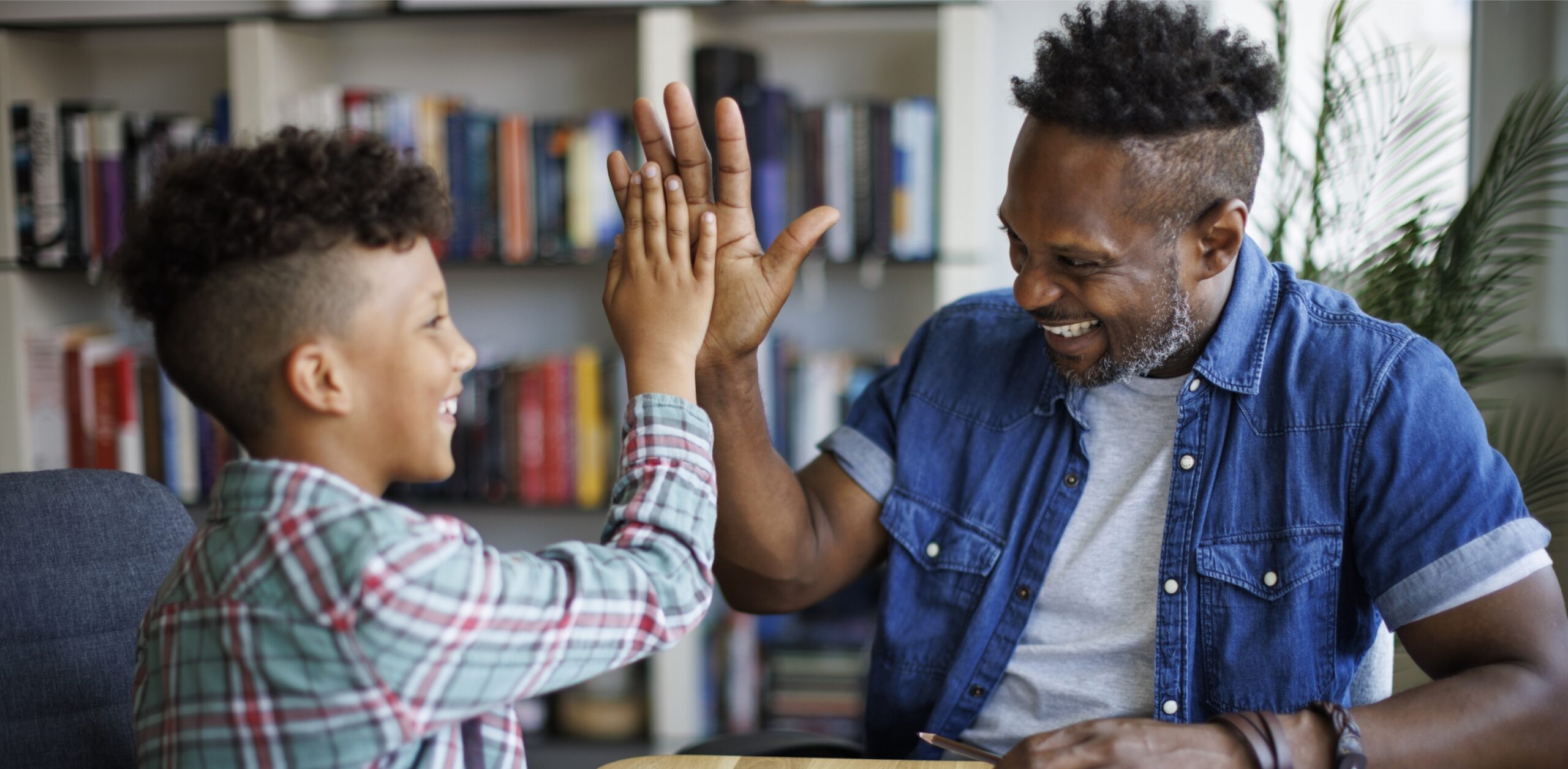 A smiling dad high fives his son