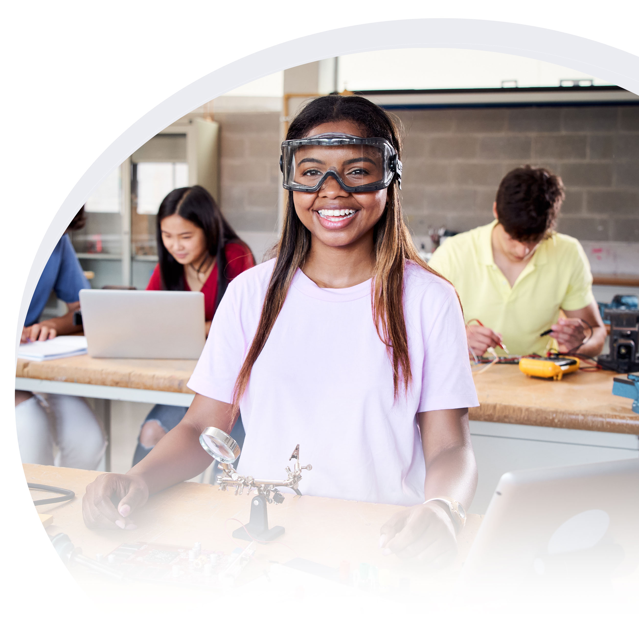 A smiling young woman with protective eye gear in a student lab
