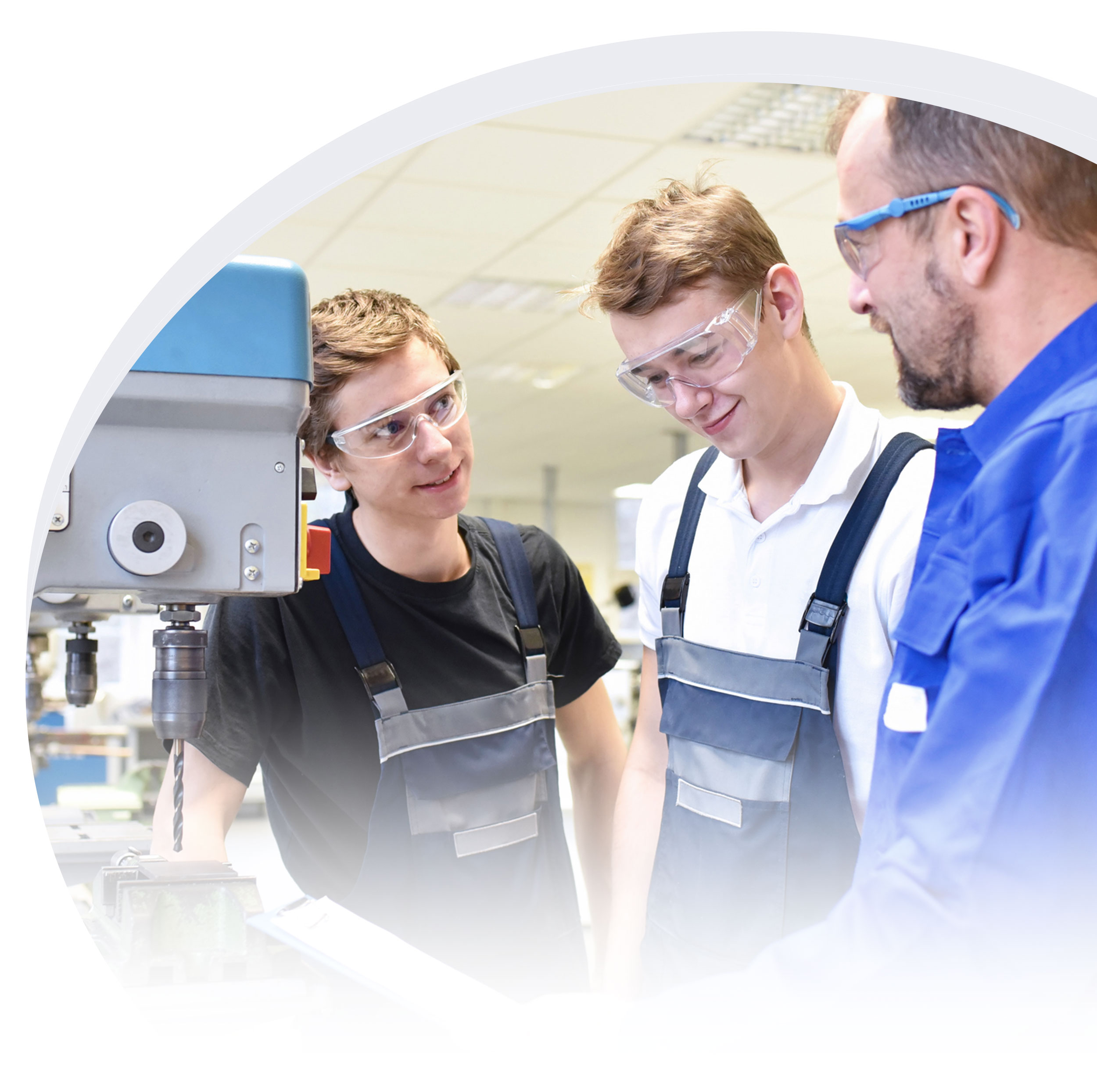 Two young technicians in protective eye gear learning from an older technician