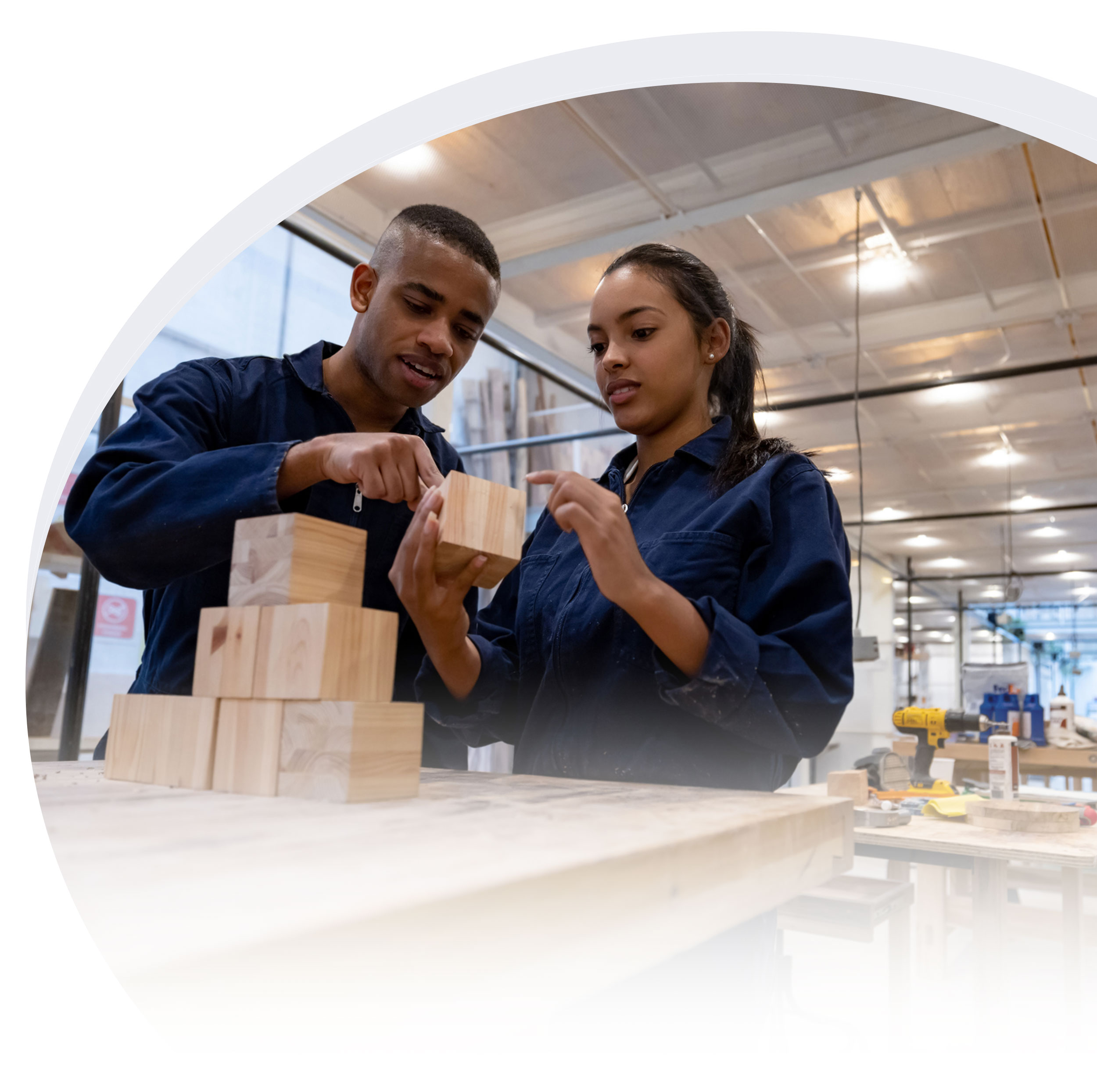 Two technicians in blue jumpsuits working with wooden blocks
