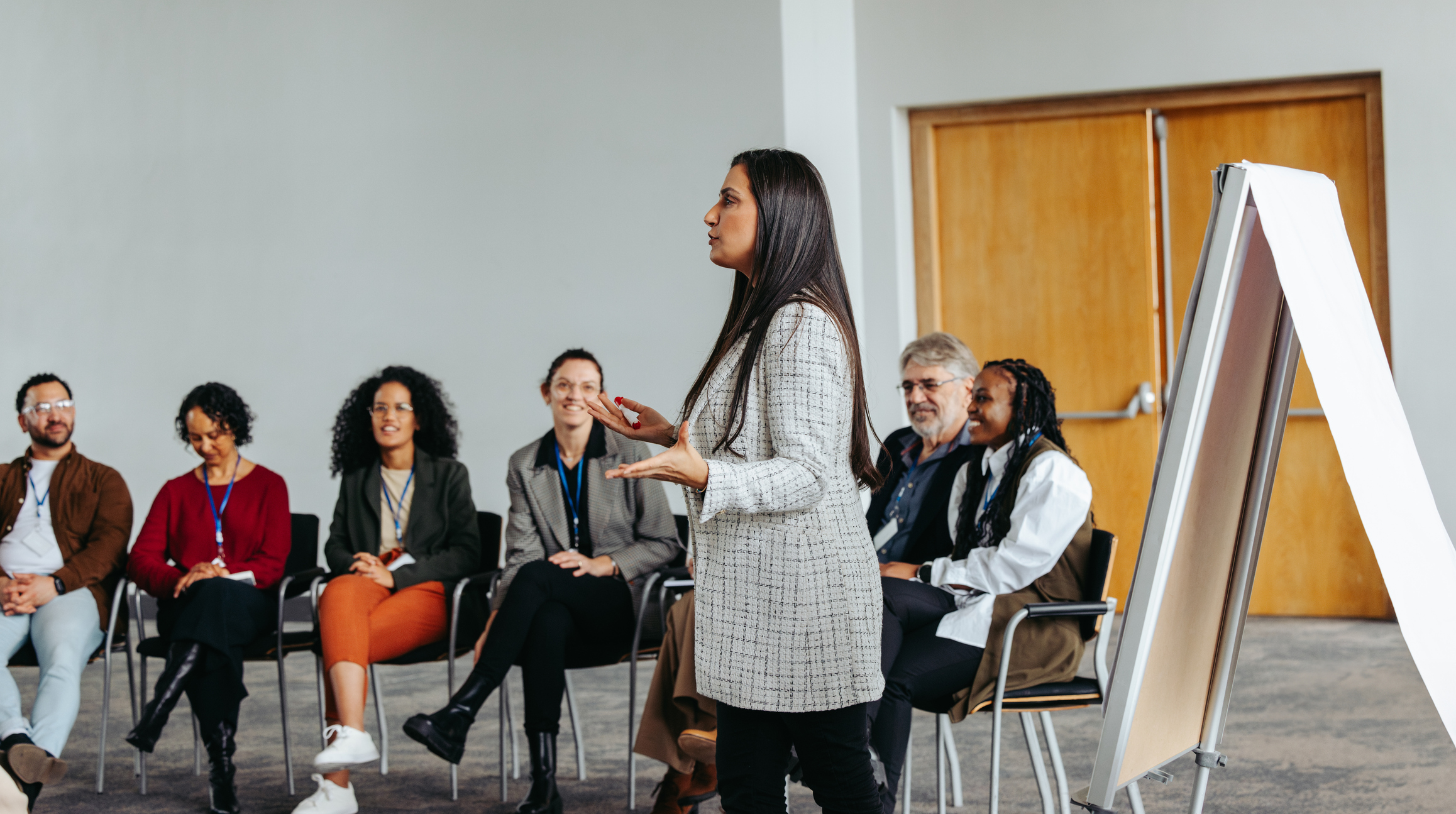 A female instructor engaging with a diverse team in a teambuilding session at a modern office, fostering collaboration and teamwork.